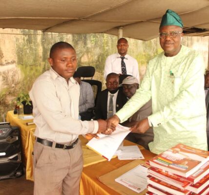 Dr. Adeniran presenting promotion letters to a teacher