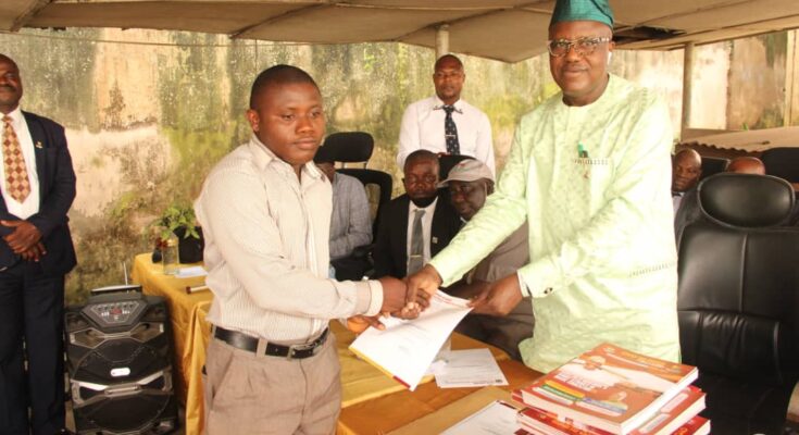 Dr. Adeniran presenting promotion letters to a teacher